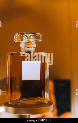Transparente Flasche imitierte Parfüm vor goldenem Hintergrund. Lux-Flasche auf einem Ständer. Design Template für luxuriöse Parfümerie. Сopy Raum Stockfoto