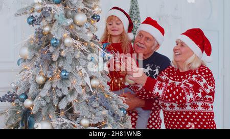 Glückliche Großeltern, Enkelin Kleinkind Kind hängen Kugeln Dekoration Weihnachtsbaum feiern Stockfoto