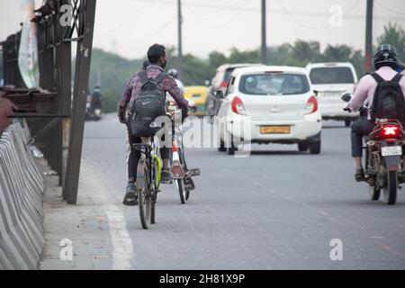 Mann auf altem gebrochenem Fahrrad, der mit Autos und mehr auf einer befahrenen Straße auf einem Tag voller Nebelsmog-Verschmutzung in der National Capital Region unterwegs war Stockfoto