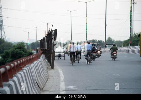 Mann auf altem gebrochenem Fahrrad, der mit Autos und mehr auf einer befahrenen Straße auf einem Tag voller Nebelsmog-Verschmutzung in der National Capital Region unterwegs war Stockfoto