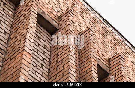 Abstrakte Stadtarchitektur Hintergrund, Backsteinmauer mit Dekorationselementen ist unter hellem Himmel Stockfoto
