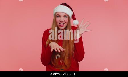 Verrücktes Mädchen in Weihnachten Santa Pullover Hut Demonstration Zunge aus Narren um dumme Gesichter zu machen Stockfoto