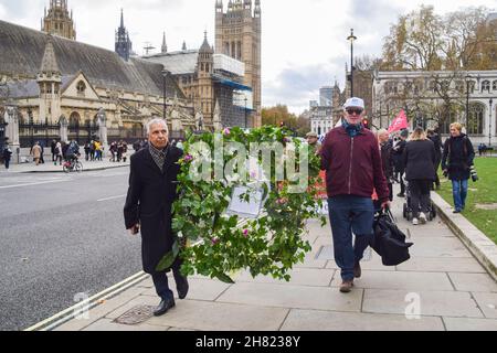 London, Großbritannien. 26th. November 2021. Demonstranten marschieren mit einem Kranz zu Ehren von 63.000 Menschen, die im Winter 2020-2021 während der Demonstration auf dem Parliament Square starben.Demonstranten versammelten sich vor dem Parlament und marschierten in die Downing Street, um Boris Johnson einen Brief zu überreichen, in dem sie Maßnahmen gegen überflüssige Todesfälle im Winter forderten. Zehntausende von Menschen, insbesondere die ältesten und ärmsten, sterben jedes Jahr an kalten Häusern und der Unfähigkeit, sich Heizung leisten zu können. (Foto: Vuk Valcic/SOPA Images/Sipa USA) Quelle: SIPA USA/Alamy Live News Stockfoto