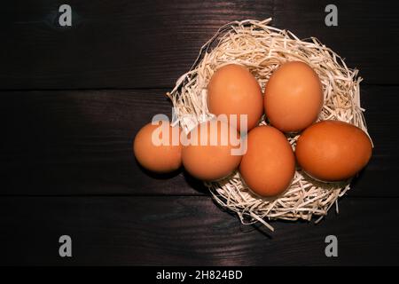 Osterbraune Eier im Nest auf dunklem Holzhintergrund Stockfoto