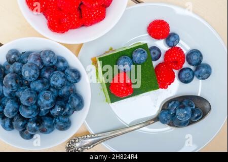 Grüner Tee Matcha Mousse Torte mit Himbeeren und Heidelbeeren an der Spitze Stockfoto