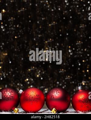 Weihnachtsschmuck Zusammensetzung der vier roten Abend Kugeln mit rot glitter Schneeflocken auf es auf dunklem Hintergrund mit Silber und Gold Farben boke Stockfoto