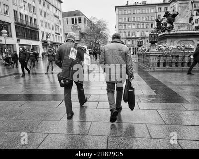 München, Bayern, Deutschland. 26th. November 2021. Ein Mann in München, Deutschland, trägt ein Trennglas über den Marienplatz. Das Glas weist immer noch Anzeichen auf, dass es verwendet wurde, um die Ausbreitung des Coronavirus zu verlangsamen oder zu verhindern. (Bild: © Sachelle Babbar/ZUMA Press Wire) Bild: ZUMA Press, Inc./Alamy Live News Stockfoto