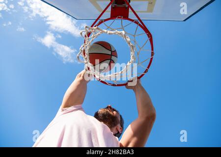 Guy dunking Basketball Ball durch Netzring mit Händen, gewinnen Stockfoto