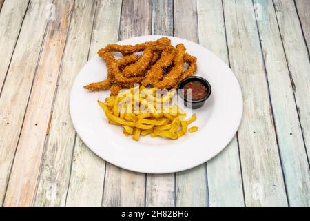 Hähnchenstreifen in Teig und in Olivenöl gebraten garniert mit hausgemachten Chips und Dipping Sauce Stockfoto