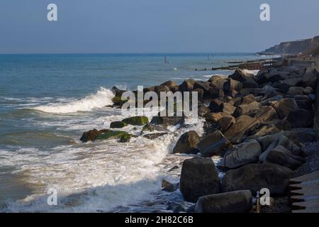 Wellen brechen auf schützenden Wellenfelsen unterhalb der Strandpromenade von Sheringham an der Nordküste von Norfolk, East Anglia, England Stockfoto
