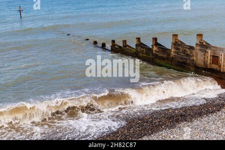 Die Wellen brechen am Ufer des Kiesstrandes durch typische hölzerne Groynes in Sheringham, einer Küstenstadt an der nördlichen Norfolk-Küste, East Anglia, England Stockfoto