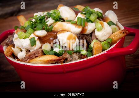 Entenconfit-Poutine-Gericht auf Holztisch Poutine ist eine kanadische Mahlzeit mit pommes Frites-Sauce und Käsekrümmen Stockfoto