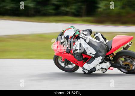 Motorrad-Praxis lehnt sich in eine schnelle Ecke auf der Strecke Stockfoto