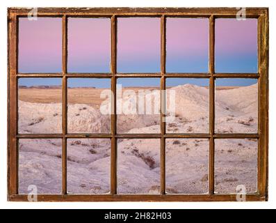 Dämmerung über Badlands und Prärie in Colorado, von einem alten Schiebefenster aus gesehen Stockfoto