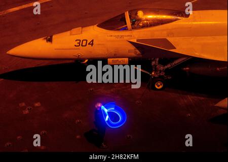 Philippinische See. 18th. November 2021. Ein Seemann leitet eine F/A-18E Super Hornet, die den 'Goldenen Drachen' des Strike Fighter Squadron (VFA) 192 zugewiesen wurde, auf dem Flugdeck des Nimitz-Klasse-Flugzeugträgers USS Carl Vinson (CVN 70), 18. November 2021. Die Carl Vinson Carrier Strike Group ist im geplanten Einsatzbereich der US-Flotte für 7th im Einsatz, um die Interoperabilität durch Allianzen und Partnerschaften zu verbessern und gleichzeitig als einsatzbereite Truppe zur Unterstützung einer freien und offenen Region im Indo-Pazifik-Raum zu dienen. Quelle: U.S. Navy/ZUMA Press Wire Service/ZUMAPRESS.com/Alamy Live News Stockfoto