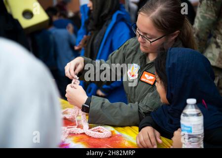 13. November 2021 - Joint Base McGuire-Dix-Lakehurst, New Jersey, USA - 1st LT. Amber Reichart, Task Force Liberty, lehrt ein afghanisches Kind während einer Herbstfeier in Liberty Village auf Joint Base McGuire-Dix-Lakehurst, New Jersey, 13. November 2021, wie es stricken kann. Das Verteidigungsministerium stellt über das Northern Command der USA und zur Unterstützung des Heimatschutzministeriums so schnell wie möglich Transport, vorübergehende Unterbringung, medizinische Vorsorgeuntersuchungen und allgemeine Unterstützung für mindestens 50.000 afghanische Evakuierte in geeigneten Einrichtungen, in permanenten oder temporären Strukturen bereit. Diese Initiative p Stockfoto