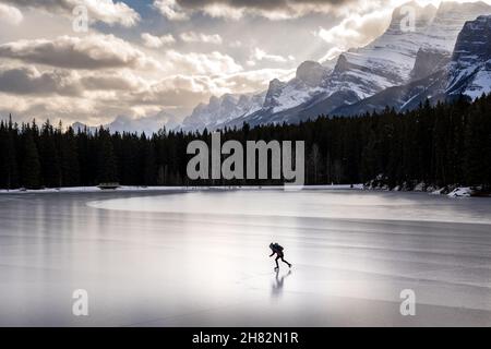 Eine Person Schlittschuhlaufen auf einem gefrorenen Bergsee im Banff National Park Stockfoto