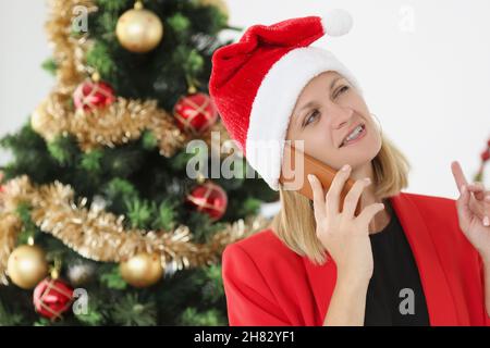 Geschäftsmann telefoniert in weihnachtsmannhut vor dem Hintergrund des Neujahrsbaums Stockfoto
