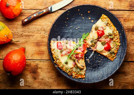 Pizza mit Salami, Käse, Tomate auf einem Kürbis-Fladenbrot. Herbstrezept Stockfoto