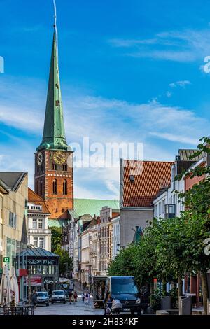 Der Kirchturm der St.-Jakobi-Kirche mit ihrem grünen Kirchturm überragt die Straßen und Gebäude von Lübeck. Lübeck, Deutschland Stockfoto