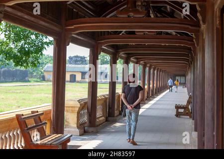 Frau, die in der Long Gallery (Hữu Trường lang), Purple Forbidden City, Hue, Vietnam, spazierengeht. MODELL FREIGEGEBEN Stockfoto