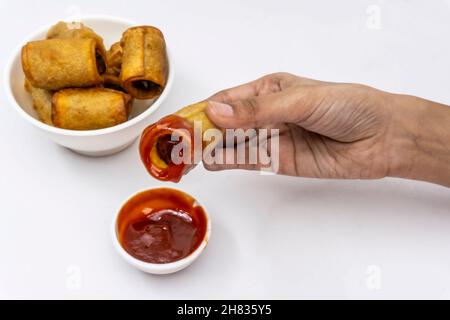 Kartoffelrollen In Der Hand Und In Tomatensauce Getaucht, Nahaufnahme Stockfoto