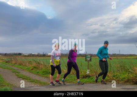 Joggen in Leyland, Lancashire, Großbritannien. 27. November 2021. Sturmhimmel, heftige Schauer und kalte Bedingungen im ländlichen Lancashire für Jogger, die morgens auf Privatgelände Sport treiben. Kredit: MediaWorldImages/AlamyLiveNews Stockfoto