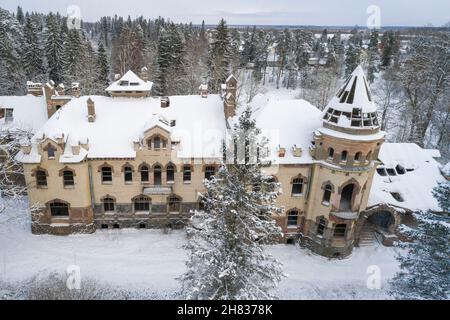 Über dem alten verlassenen Hauptgebäude des Eliseevs-Anwesens (1912) an einem bewölkten Februartag. Belogorka, Region Leningrad. Russland Stockfoto