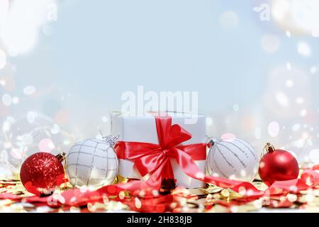 Weiße Geschenkbox mit rotem Band und weihnachtskugeln. Weihnachtskarte. Stockfoto