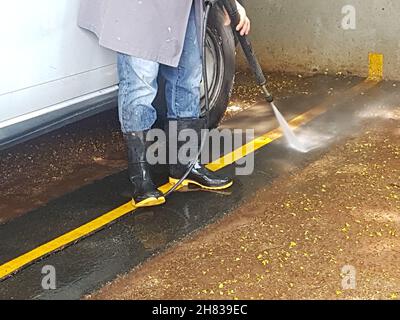 Gummistiefel, die Füße der Männer sind beim Waschen des Bodens mit der Maschine geschützt. Stockfoto