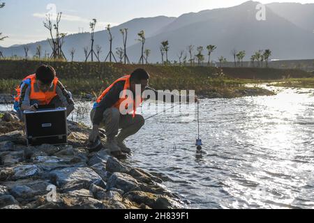 Guiping, China. 26th. November 2021. (211127) -- GUIPING, 27. November 2021 (Xinhua) -- Mitarbeiter stellten eine Kamera ins Wasser, um den Fischweg des Hilfsdamms im Nanmu-Fluss, der Teil des Wasserschutzprojekts der Dateng-Schlucht ist, in Guiping, Südchina, Autonome Region Guangxi Zhuang, am 26. November 2021 zu überwachen. Das Wasserkraftprojekt basiert auf dem Gebiet, das aufgrund seiner komplexen Strömungsverhältnisse ein wichtiger Lebensraum für Fische ist. Quelle: Xinhua/Alamy Live News Stockfoto