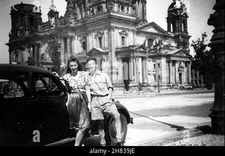 Im August 1947 besuchte der RAF-Pilot Browne Berlin und nahm eine Begleiterin mit auf eine Sightseeing-Tour durch die Stadt. Hier stehen sie vor den Ruinen der Freien Kathedrale. Das Mädchen ist unbekannt, möglicherweise eine Kellnerin, die an ihrer Schürze vorbei geht. P/O Browne flog am 12th. August 1947 nach Berlin Gatow und am 19th. August 1947 nach RAF Bückeberg. Stockfoto