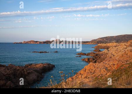 Luftaufnahme einer felsigen Küste und ruhiges Meerwasser, das wunderschön in der Sonne scheint. Drohne, die zwischen Felsformationen fliegt. Stockfoto