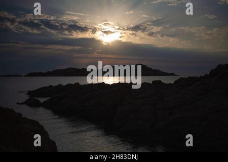 Luftaufnahme einer felsigen Küste und ruhiges Meerwasser, das wunderschön in der Sonne scheint. Drohne, die zwischen Felsformationen fliegt. Stockfoto