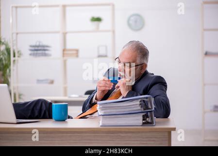 Ein alter Geschäftsmann, der seine Kreditkarte im Büro hält Stockfoto