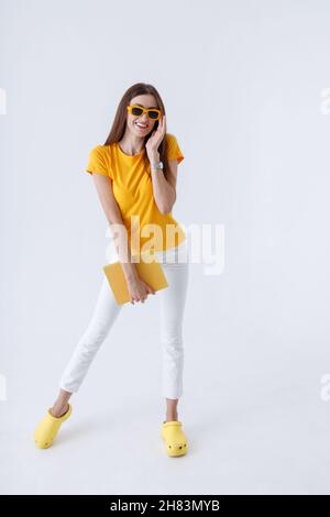 Fröhliche Frau mit Buch, das im Studio steht Stockfoto