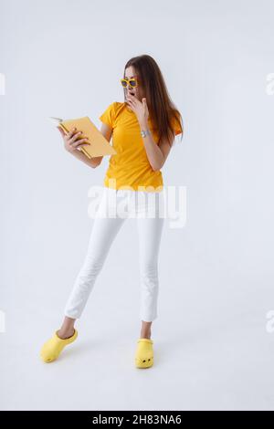Charmante schockierte Frau, die im Studio ein Buch liest Stockfoto