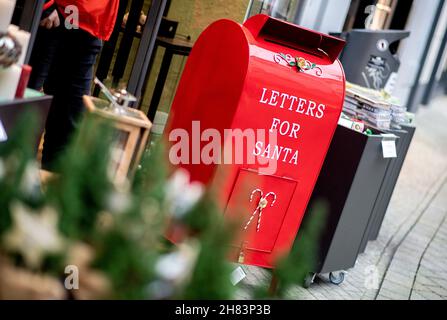 Oldenburg, Deutschland. 27th. November 2021. Ein roter Briefkasten mit der Aufschrift 'Briefe für den Weihnachtsmann' steht vor einem Geschäft im Stadtzentrum. Auch in diesem Jahr ist das Weihnachtsgeschäft in den niedersächsischen Innenstädten von einer schweren Corona-Delle bedroht. Angesichts der rasant steigenden Infektionszahlen erwägt die Landesregierung auch strengere Anforderungen an Einzelhändler, beispielsweise in Form von obligatorischen Tests. Quelle: Hauke-Christian Dittrich/dpa/Alamy Live News Stockfoto