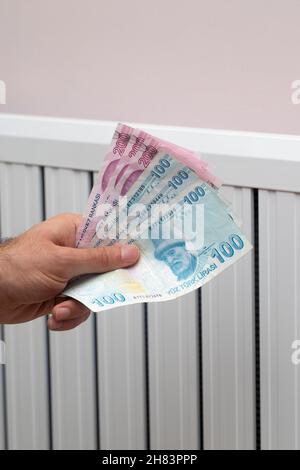 Energiekrise in der Türkei. Anstieg der Gaspreise in Europa für die Bevölkerung. Türkische Lira vor einem brennenden Heizkörper Stockfoto