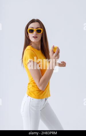 Charmante Frau in stilvollen Sonnenbrille hält Parfüm Stockfoto