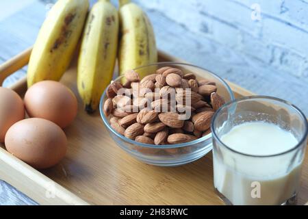 Eier in einem Plastikbehälter, Milch und Mandelnuss auf dem Tisch Stockfoto