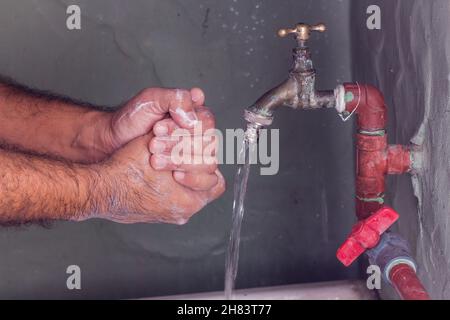 Mann, der sich in einer schlechten Toilette mit neutraler Seife und Wasser die Hände wusch Stockfoto