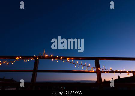 Weihnachtslichter am Geländer eines Balkons in der Nacht Stockfoto