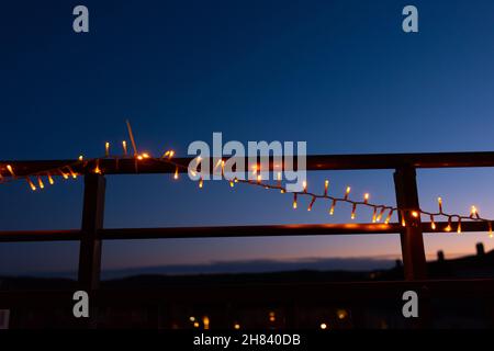 Weihnachtslichter am Geländer eines Balkons in der Nacht Stockfoto