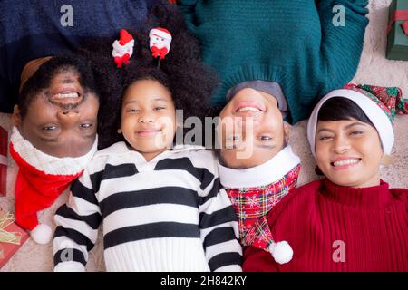 Glückliche afrikanische Familie liegt lächelnd am Weihnachtstag zusammen, während Geschenkbox auf dem Boden, Draufsicht, Beziehung und Bindung der Familie, Feier und ho Stockfoto