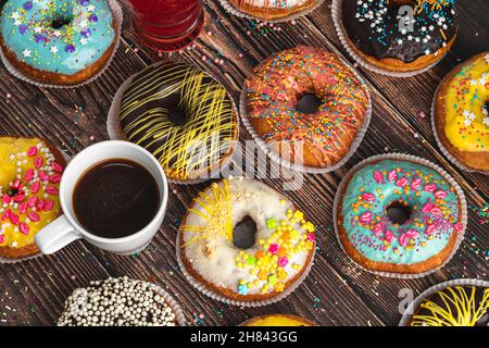 Draufsicht auf Donuts in verschiedenen Farben und Geschmacksrichtungen auf Holztisch Stockfoto
