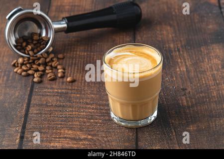 Cortado-Kaffee mit Kaffeebohnen daneben. Traditioneller Kaffee in Spanien. Stockfoto