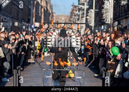 Glasgow, Schottland, Großbritannien. 27th. November 2021: Der Straßenkünstler Liam Collins, bekannt als The Stunt Runner, führt Straßentheater in der Buchanan Street auf, um die Weihnachtseinkäufer zu unterhalten. Der Künstler wird mit verbundenen Augen geführt und springt durch Metallarbeiten, umgeben von Messern, Stacheln, Metallzähnen und Flammen. Kredit: Skully/Alamy Live Nachrichten Stockfoto