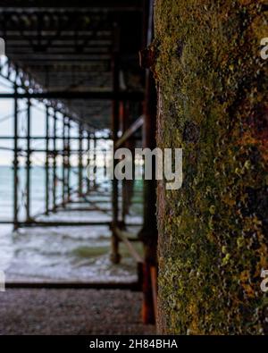 Kleine und mittlere Wellen brechen gegen die Unterseite des Hastings Pier, Sussex, Großbritannien. Stockfoto