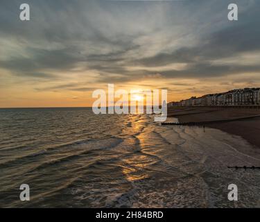 Sonnenuntergang und goldene Stunde am Hastings Pier, England, Großbritannien mit Blick auf Eastbourne mit dem Meer und den Groynes im Vordergrund.Promenade Stockfoto